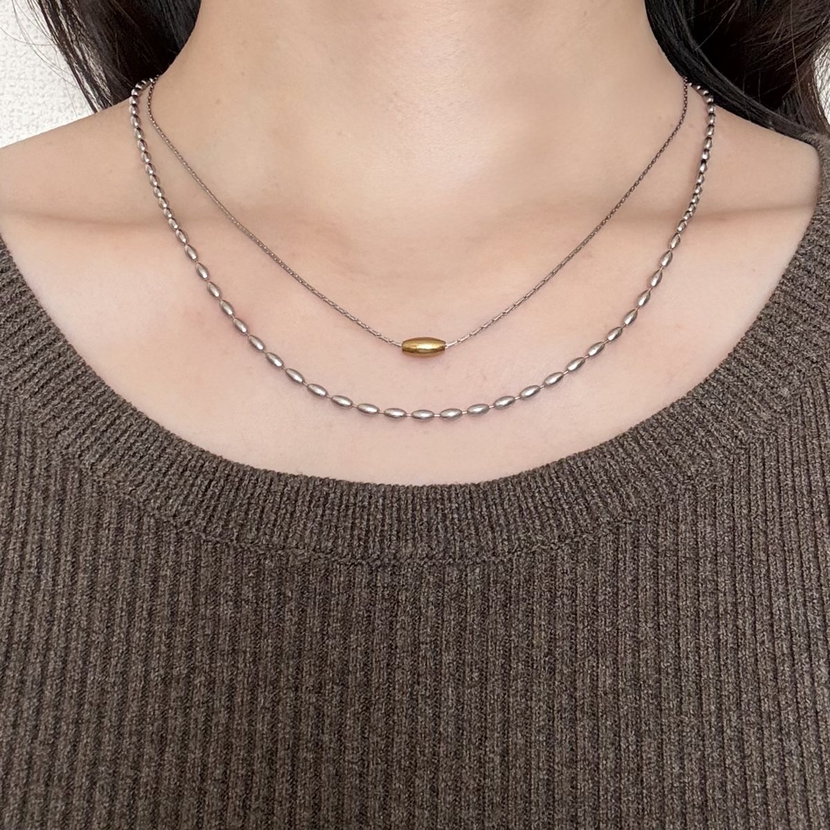 ブラウンのリブニットにAJIROのダブルチェーンネックレスをつけた首元